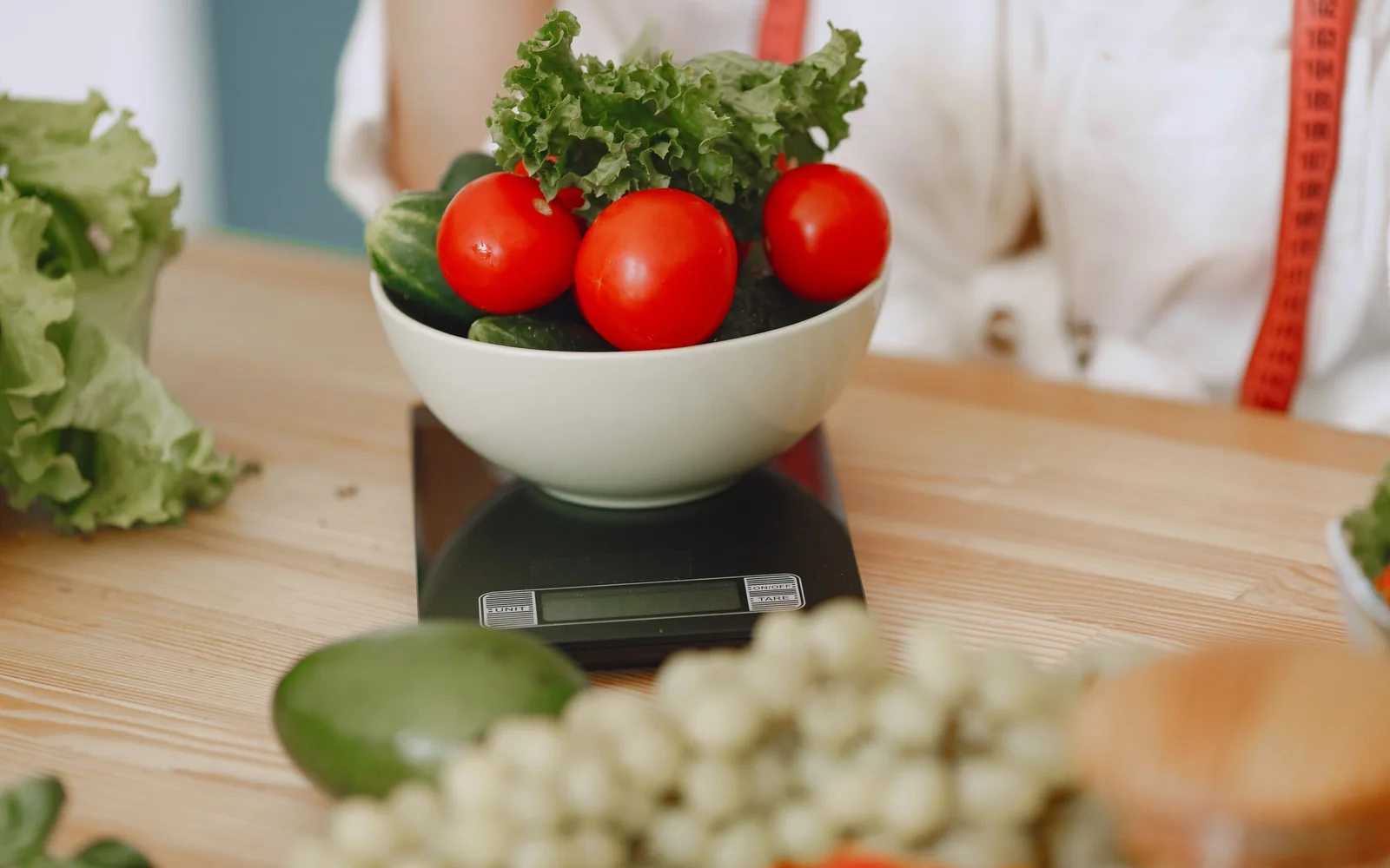 A bowl of tomatoes and lettuce on a digital kitchen scale.